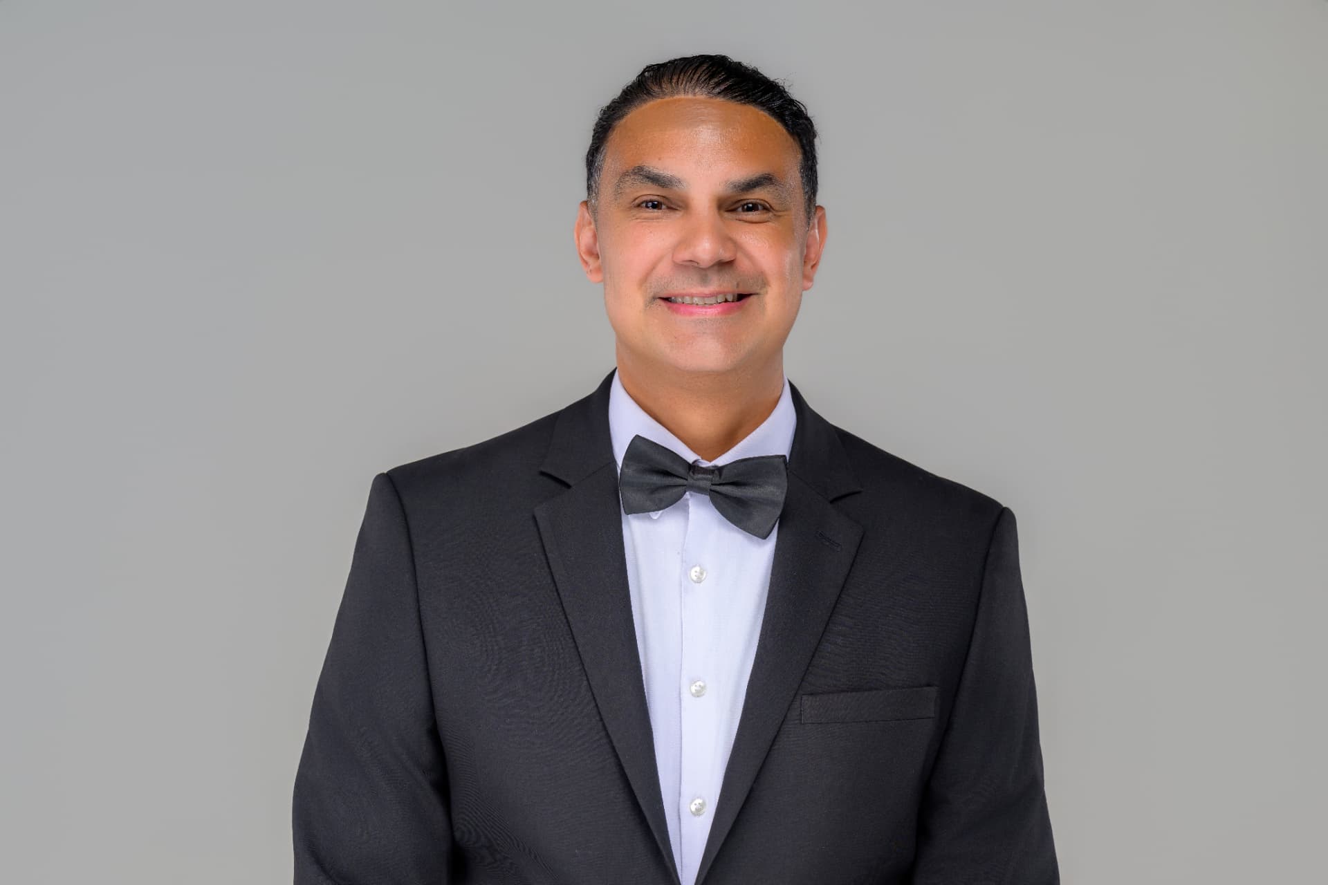 Angel Alba in a tailored tuxedo — bilingual New England wedding DJ and Master of Ceremonies